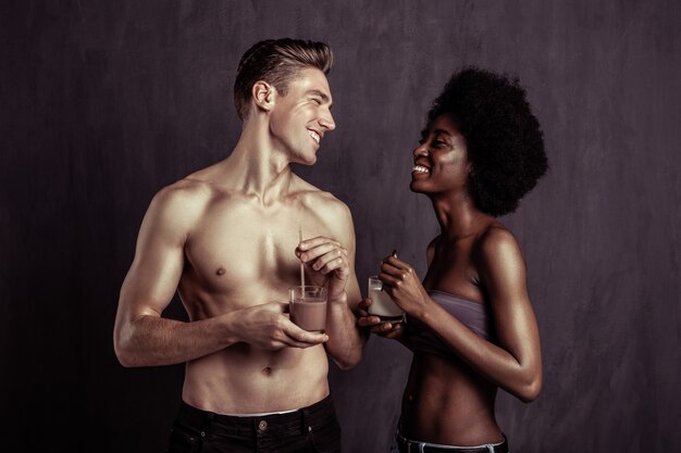 Absolutamente delicioso. Casal alegre e encantado sorrindo um para o outro enquanto saboreia seus deliciosos coquetéis