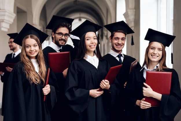 Absolventen stehen mit Diplomen in der Lobby der Universität.