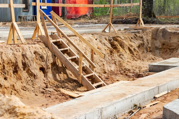 Abstieg in eine tiefe Baugrube beim Hausbau Gebäudesicherheitsleiter zum Abstieg auf Stahlbetonfundamente