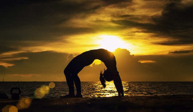 Abstrac. Yoga de silueta. Retrato de mujer joven practicando yoga en el mar. Relajarse en el mar. Meditación