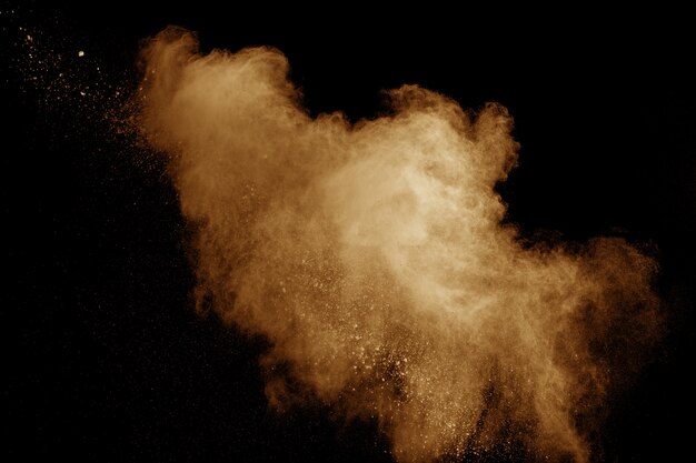 Abstrakte orange staubexplosion auf schwarzem hintergrund