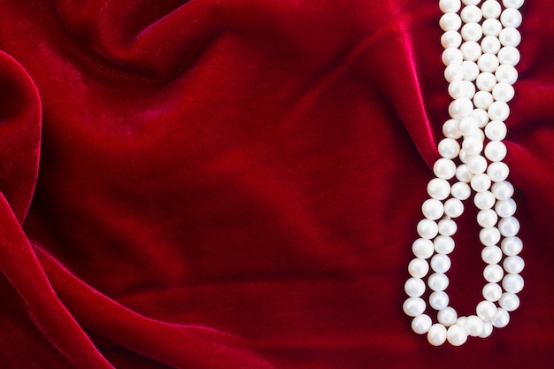 Abstrakte Textur des drapierten roten Samthintergrundes mit Perlen