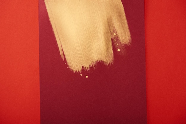 abstrakter Burgunder-Hintergrund mit goldenem Pinselstrich isoliert auf rot