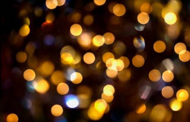 Abstrakter festlicher verschwommener Hintergrund von goldenen Bokeh-Lichtern auf Schwarz