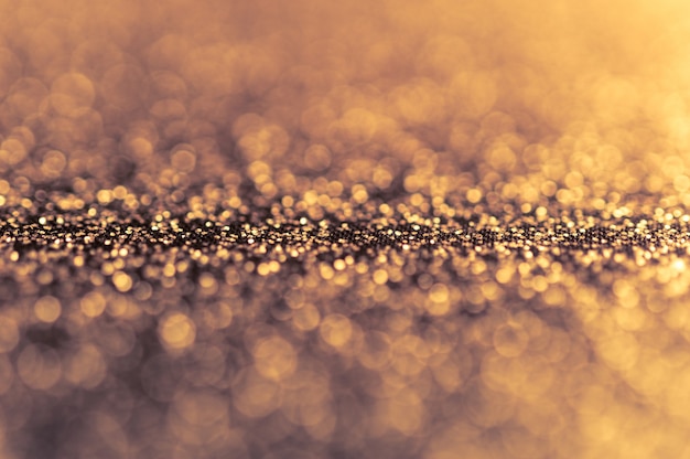 Foto abstrakter glänzender goldener hintergrund mit bokeh und defokussierten lichtern. glitzer leuchtendes texturmuster. selektiver fokus. geringe schärfentiefe. thema weihnachten.