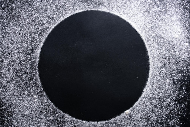 Abstrakter Hintergrund Bestreuter Weizenmehlkreis runder Fleck auf schwarzem Draufsicht auf Tafel Backkonzept, das Teig oder Gebäck kocht