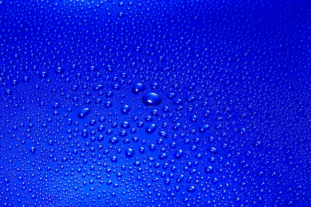Abstrakter Hintergrund Wassertropfen auf einer blauen glänzenden Oberfläche