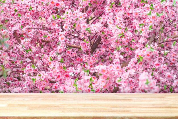 Abstrakter Tisch aus Naturholz mit künstlichen Sakura-Blumen zur Dekoration im japanischen Stil. Frühlingsblüten. Ansicht von oben aus Plankenholz für grafisches Standprodukt, Innenarchitektur oder Montage von Ausstellungsprodukten