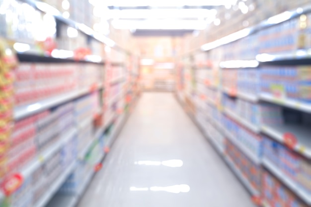 Abstrakter verschwommener Supermarktgang mit bunten Regalen und nicht erkennbaren Kunden als Hintergrund