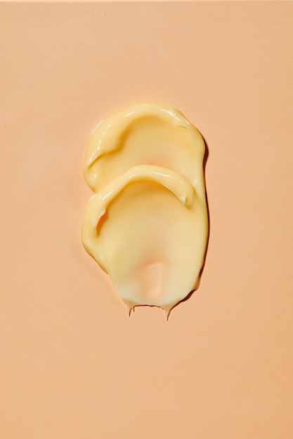 Abstrich von gelber Creme auf gelbem Hintergrund Schönheitscreme-Abstrich-Swatch-Cremelotion für Gesicht oder Körper