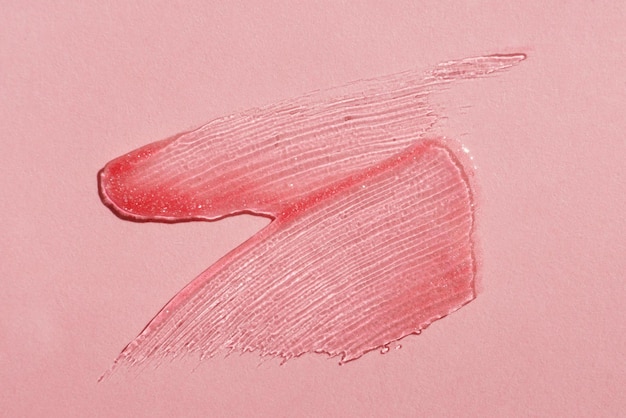 Abstriche von transparent glänzendem Lipgloss auf rosafarbenem Hintergrund