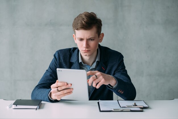 Abteilung für Personalbeschaffung. Porträt des jungen HR-Managers, der Tablet für die Arbeit verwendet. Selbstbewusster Gesichtsausdruck.