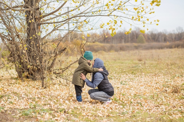 Abuela abrazando a su nieto al aire libre en el bosque de otoño