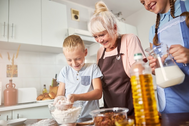 Abuela alegre y sus nietos cocinando juntos