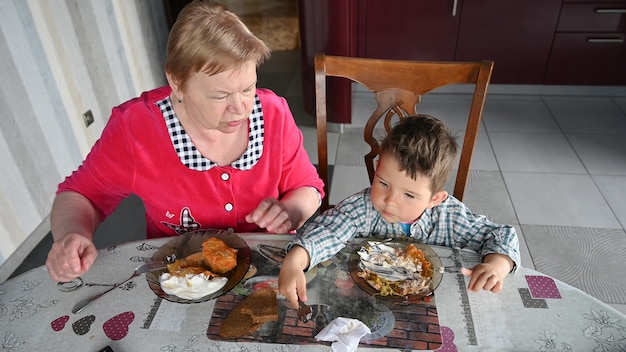 La abuela alimenta a su nieto en la cocina.