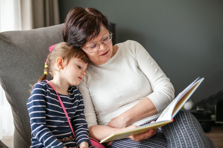 Abuela amorosa leyendo un libro a su nieta, sentada en un sillón puf. Abuela contando historias a la niña.