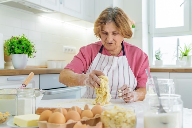 Abuela anciana en la cocina hornea prepara la masa en la cocina Enfoque selectivo Comida