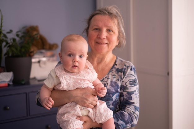 Abuela anciana sosteniendo un bebé de un mes en sus brazos