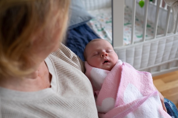 Foto abuela anciana sosteniendo a un recién nacido en sus brazos