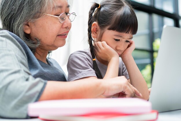 Abuela asiática con sus dos nietos divirtiéndose y jugando juegos educativos en línea