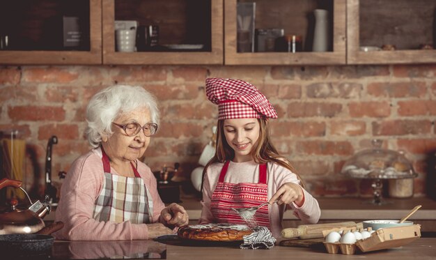 La abuela ayuda a su nieta con pastel casero