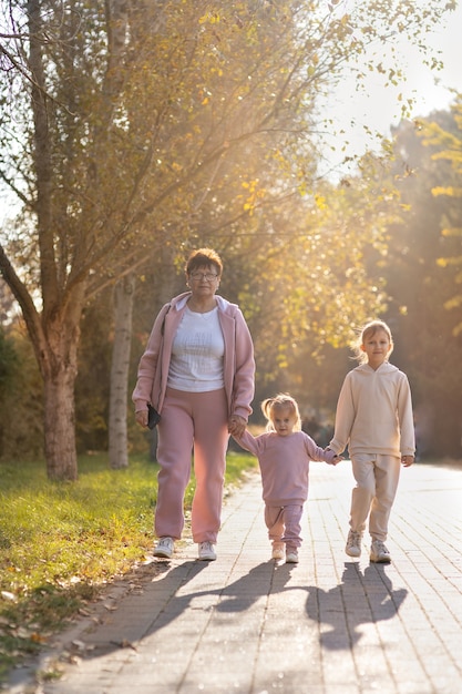 Abuela camina con sus nietos en el parque de otoño