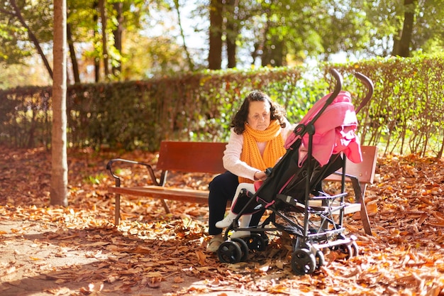 Abuela con cochecito de bebé cuidando a su nieta en el parque