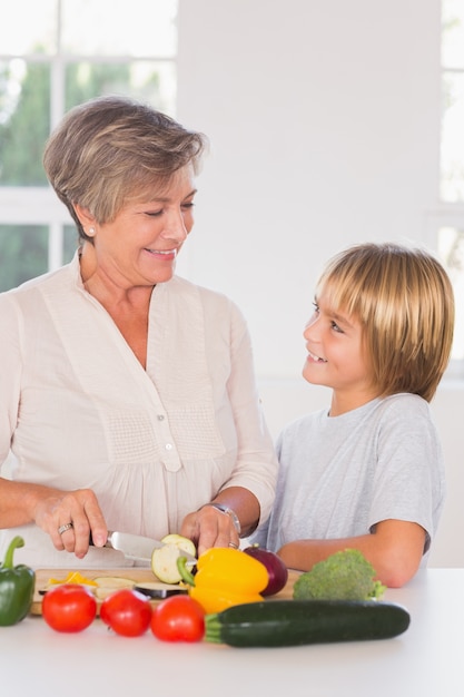 Abuela cortando verduras mirando a su nieto