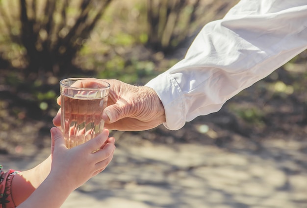 Abuela dando un vaso de agua limpia a un niño. Enfoque selectivo