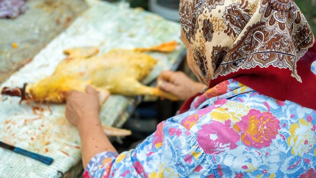 Una abuela desplumando un pato muerto. Pueblo