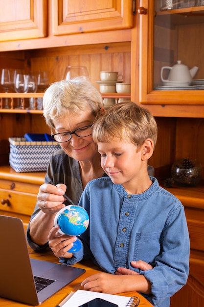 Abuela educadora en el hogar enseñando a un niño inteligente en geografía