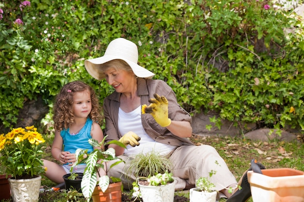 Abuela feliz con su nieta trabajando en el jardín