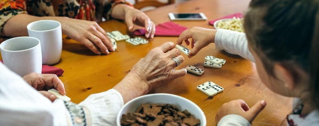 Abuela, hija y nieta irreconocibles jugando dominó en la sala de estar