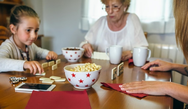 Abuela hija y nieta jugando dominó en la sala de estar