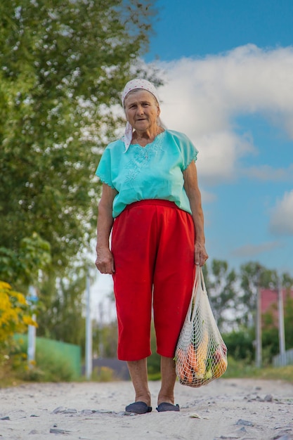 Foto abuela lleva verduras en una bolsa de compras enfoque selectivo