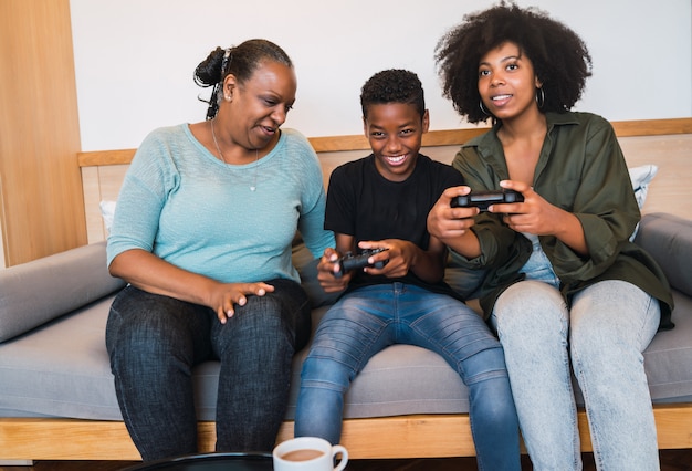 Abuela, madre e hijo jugando videojuegos en casa.