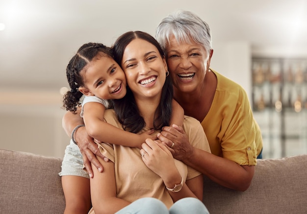 La abuela, la madre y el niño, se abrazan en un retrato para el día de la madre en un sofá de la casa como una familia feliz en Colombia Sonríe a la mamá y a la anciana les encanta abrazar a una niña o un niño y disfrutar de un tiempo de calidad