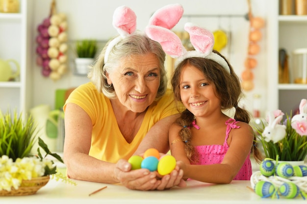 Abuela mayor y su hermosa nieta con huevos de Pascua en casa