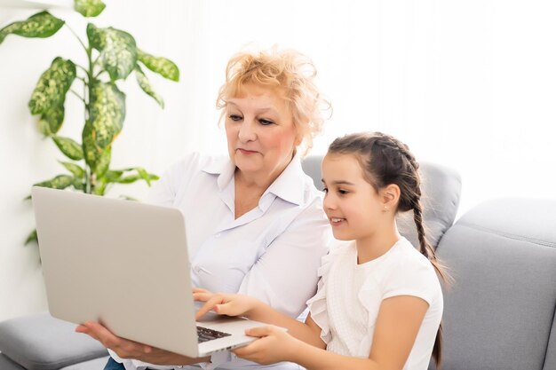 abuela moderna enseñando a su nieto cómo usar una computadora portátil en casa.