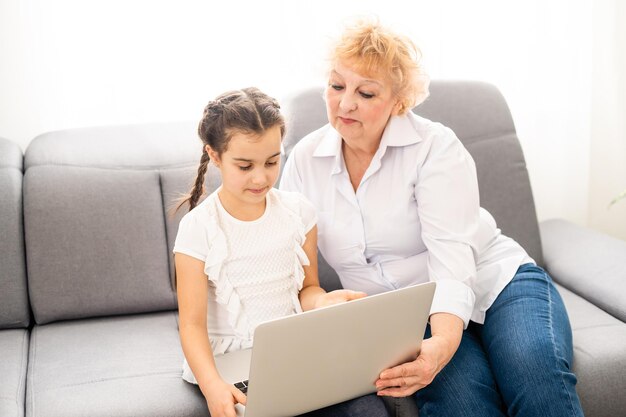 abuela moderna enseñando a su nieto cómo usar una computadora portátil en casa.
