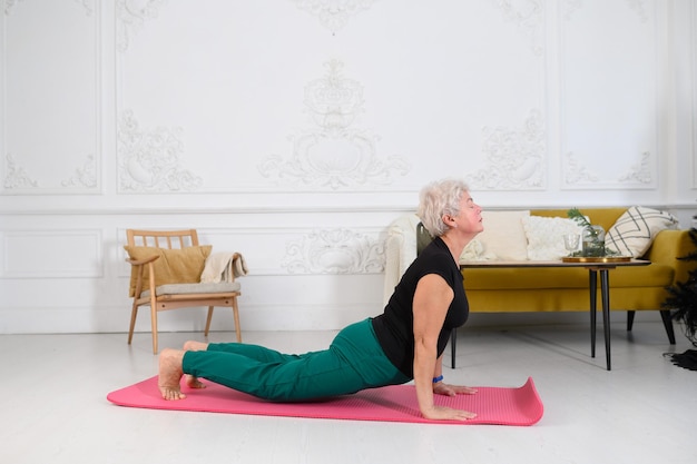 Una abuela mujer adulta hace yoga en casa practicando deportes en casa estilo de vida saludable p ...
