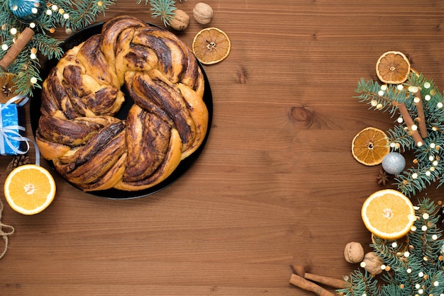 Foto abuela de navidad de chocolate en forma de corona con jarabe de naranja en un plato cortado en trozos. adornos navideños en una mesa de madera.