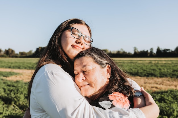 Foto abuela y nieta abrazándose en medio del campo en una tarde soleada familia