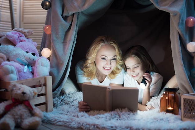 Abuela y nieta están leyendo un libro por la noche.