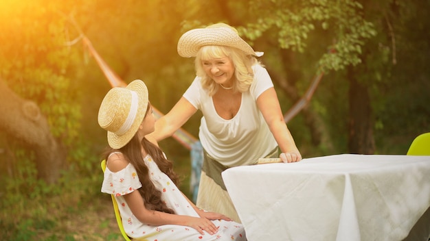 Abuela y nieta están en la mesa en el jardín