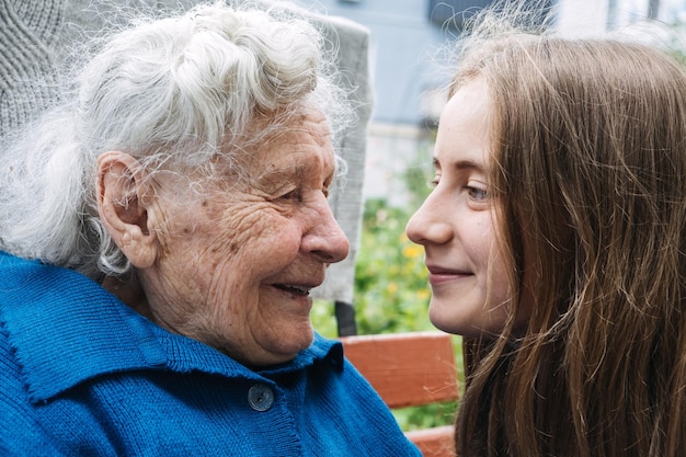 Abuela con nieta en el fondo de la naturaleza adolescente abrazando a la abuela al aire libre feliz