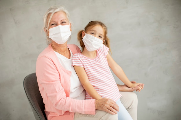 Abuela y nieta linda con máscaras respiratorias