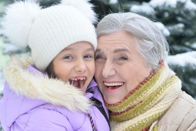 Abuela con nieta sonriendo, posando al aire libre en invierno