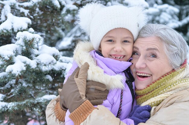 Abuela con nieta sonriendo, posando al aire libre en invierno