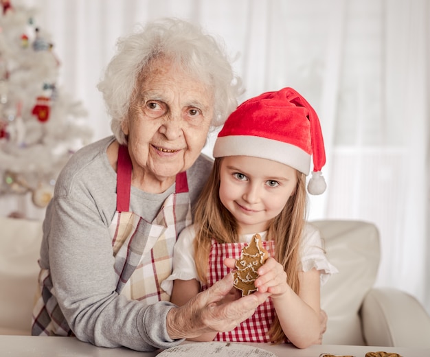 Abuela con nieta sosteniendo galletas horneadas